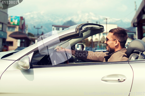 Image of happy man driving cabriolet car over city in japan