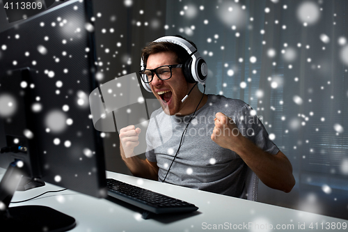 Image of man in headset playing computer video game at home