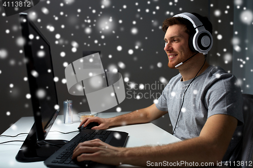 Image of man in headset playing computer video game at home