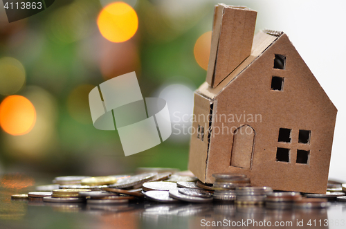 Image of Model of house with coins on wooden table