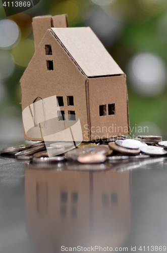 Image of Model of house with coins on wooden table