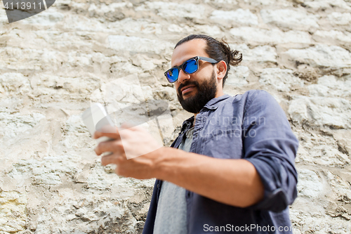 Image of man texting message on smartphone at stone wall