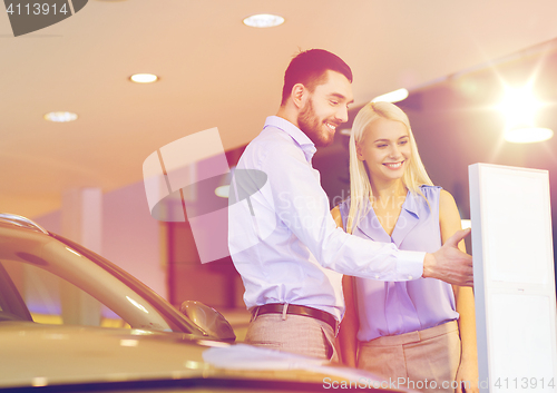 Image of happy couple buying car in auto show or salon