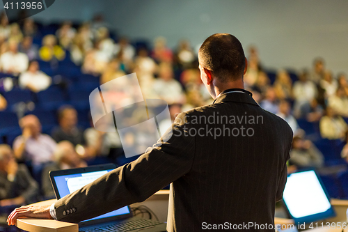 Image of Public speaker giving talk at business event.