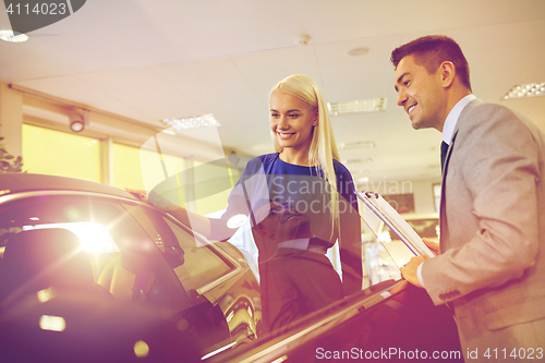 Image of happy woman with car dealer in auto show or salon