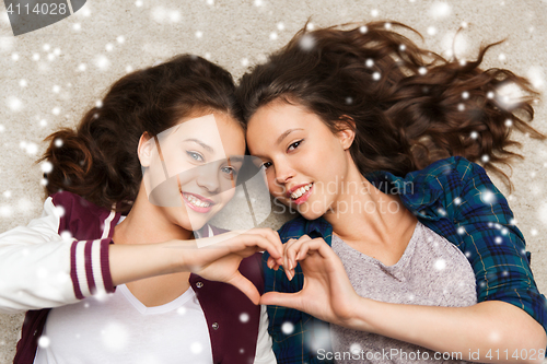 Image of happy teenage girls lying on floor with heart