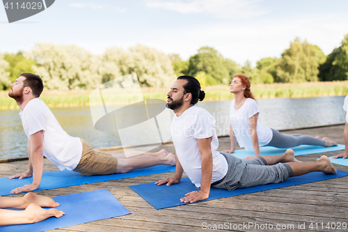 Image of group of people making yoga exercises outdoors