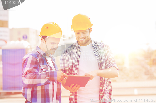 Image of smiling builders in hardhats with tablet pc