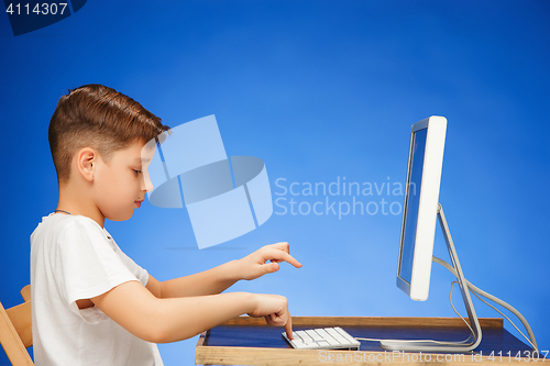 Image of School-age boy sitting in front of the monitor laptop at studio