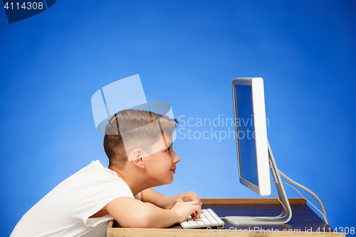 Image of School-age boy sitting in front of the monitor laptop at studio