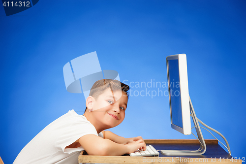 Image of School-age boy sitting in front of the monitor laptop at studio