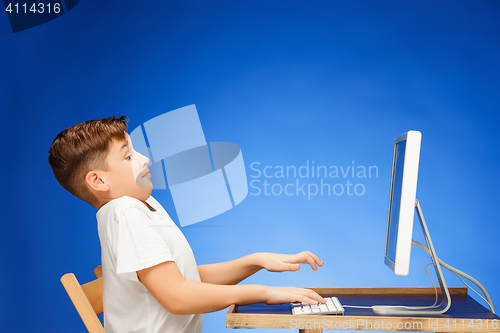 Image of School-age boy sitting in front of the monitor laptop at studio