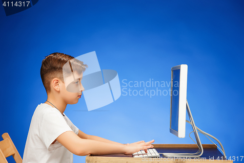 Image of School-age boy sitting in front of the monitor laptop at studio