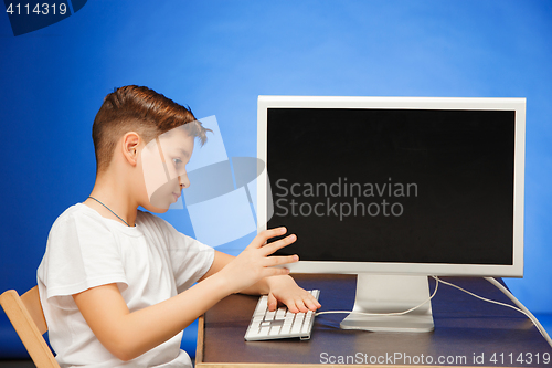 Image of School-age boy sitting with the monitor laptop at studio