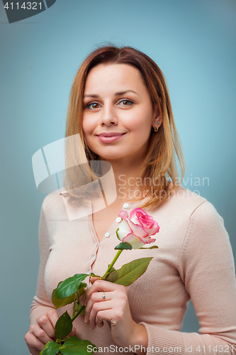 Image of Young woman holding rose and smiling