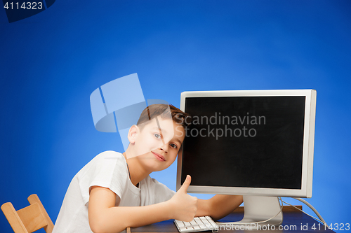 Image of School-age boy sitting in front of the monitor laptop at studio