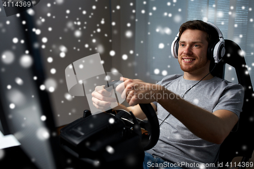 Image of man playing car racing video game at home