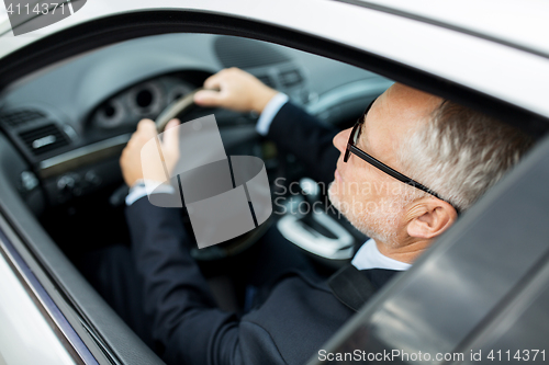 Image of happy senior businessman driving car