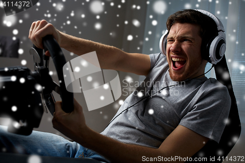 Image of man playing car racing video game at home