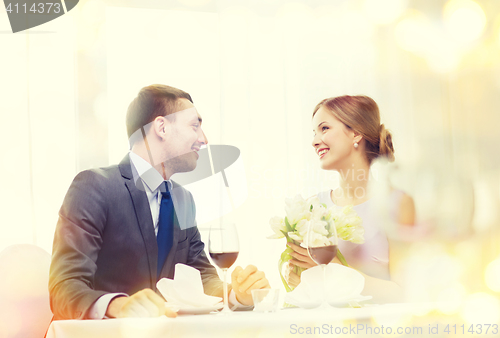 Image of smiling man giving flower bouquet at restaurant