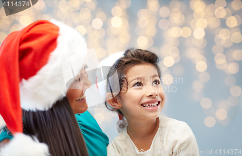Image of happy mother and little girl in santa hats