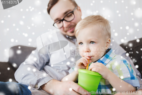 Image of father and son drinking from cup at home