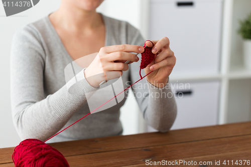 Image of woman knitting with crochet hook and red yarn