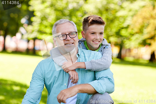 Image of grandfather and grandson hugging at summer park