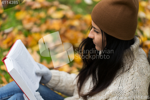 Image of close up of woman reading book in autumn park