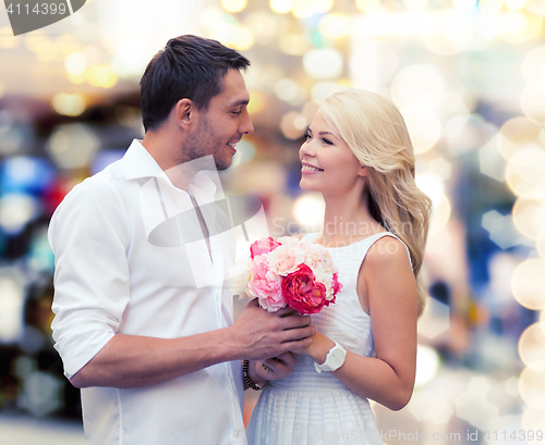 Image of happy couple with flowers over lights background