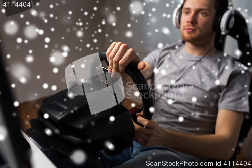 Image of man playing car racing video game at home