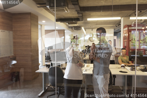 Image of young couple at modern office interior writing notes on stickers