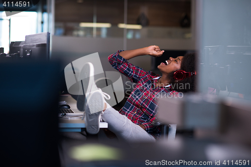 Image of woman at her workplace in startup business office listening musi