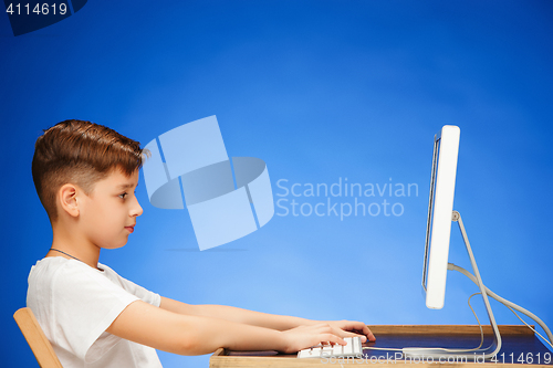 Image of School-age boy sitting in front of the monitor laptop at studio