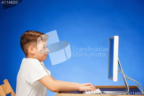 Image of School-age boy sitting in front of the monitor laptop at studio