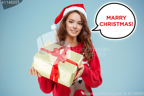 Image of Girl dressed in santa hat with a Christmas gift