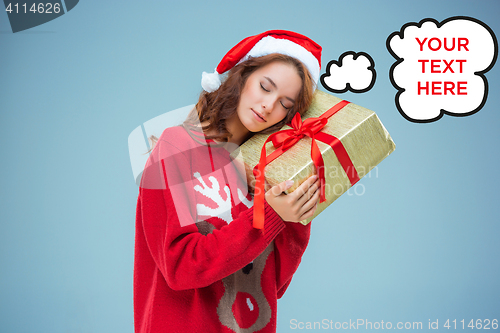 Image of Girl dressed in santa hat with a Christmas gift