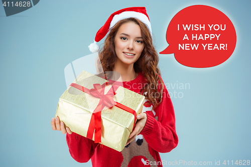 Image of Girl dressed in santa hat with a Christmas gift