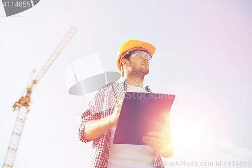 Image of builder in hardhat with clipboard outdoors