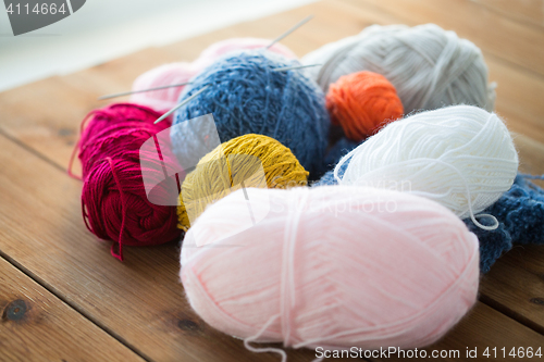 Image of knitting needles and balls of yarn on wood