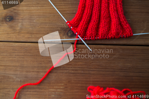 Image of hand-knitted item with knitting needles on wood