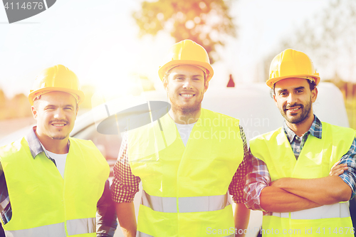 Image of group of smiling builders in hardhats outdoors