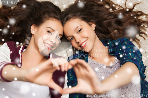 Image of happy teenage girls lying on floor with heart