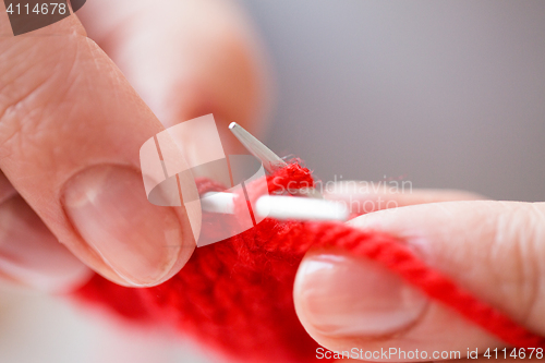 Image of close up of hands knitting with needles and yarn