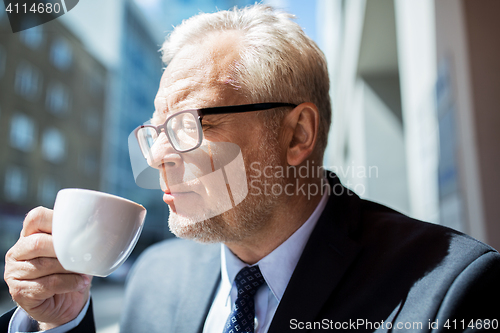 Image of senior businessman drinking coffee on city street