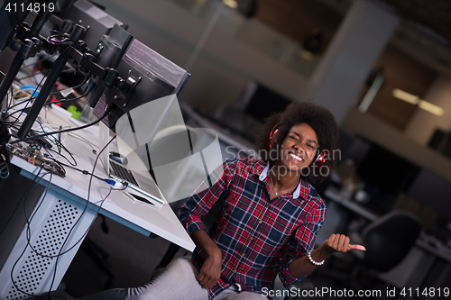 Image of woman at her workplace in startup business office listening musi