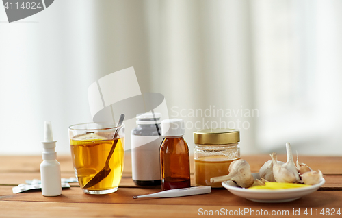 Image of drugs, thermometer, honey and cup of tea on wood