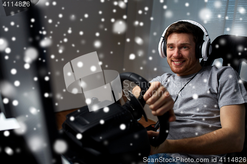 Image of man playing car racing video game at home