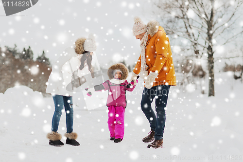 Image of happy family in winter clothes walking outdoors