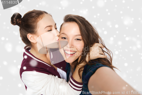 Image of happy teenage girls taking selfie and kissing